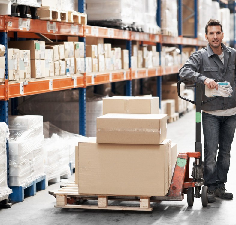 Warehouse aisle handling with a loaded trolley beside racking
